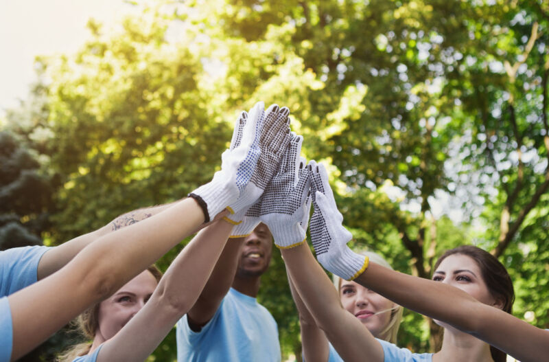 Group of volunteers making high five in park